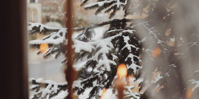 Candles on a windowsill with a snowy outdoor view