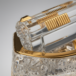 Close-up of a clear and gold decorative item with intricate patterns on a gray background